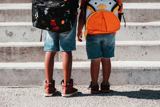 fotografía en color de dos niños que llevan mochilas