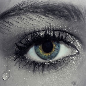 Fotografía en color y grises de ojo de mujer con lágrima
