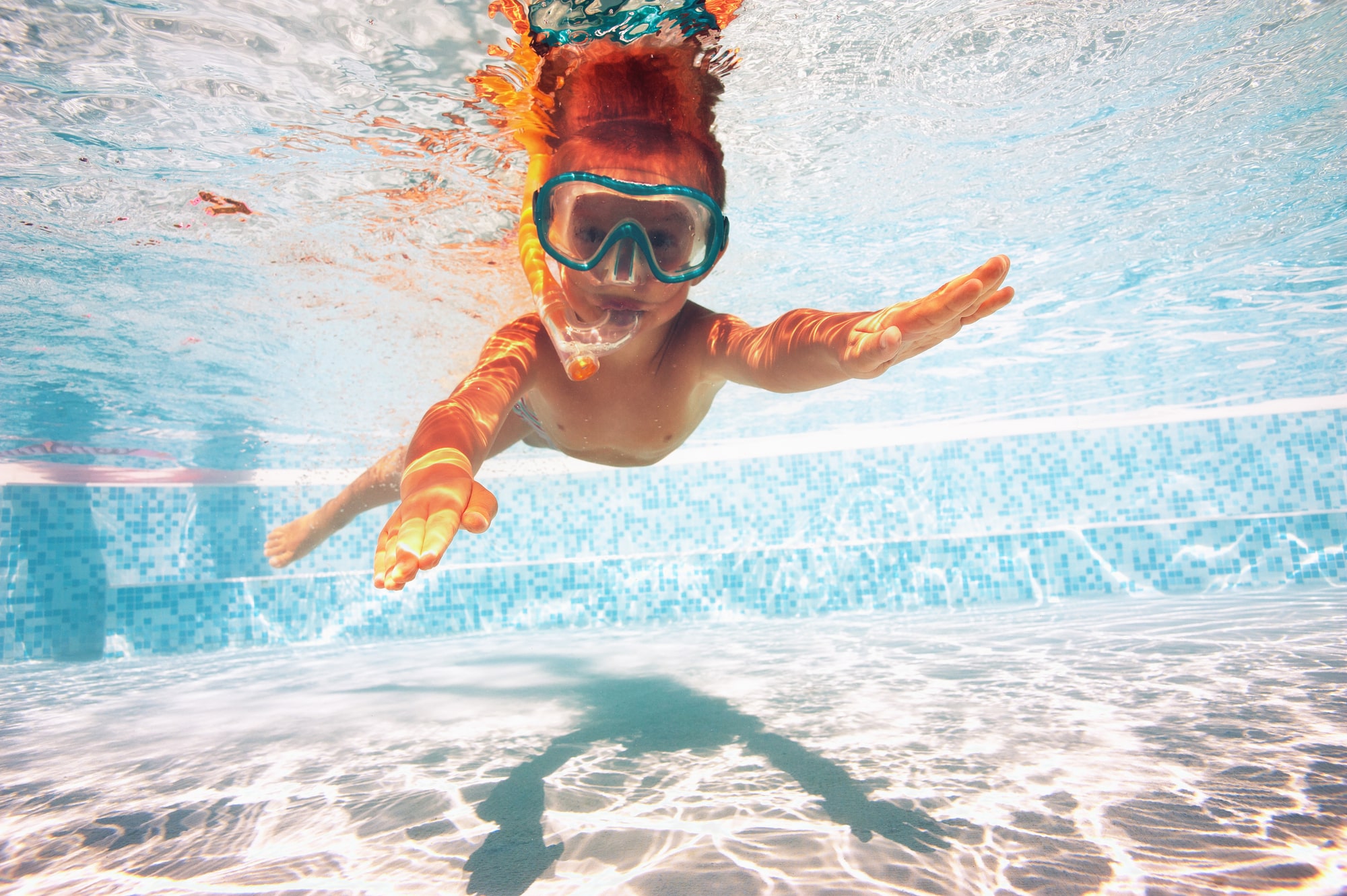 imagen en color de un niño con gafas de natación en una piscina.
